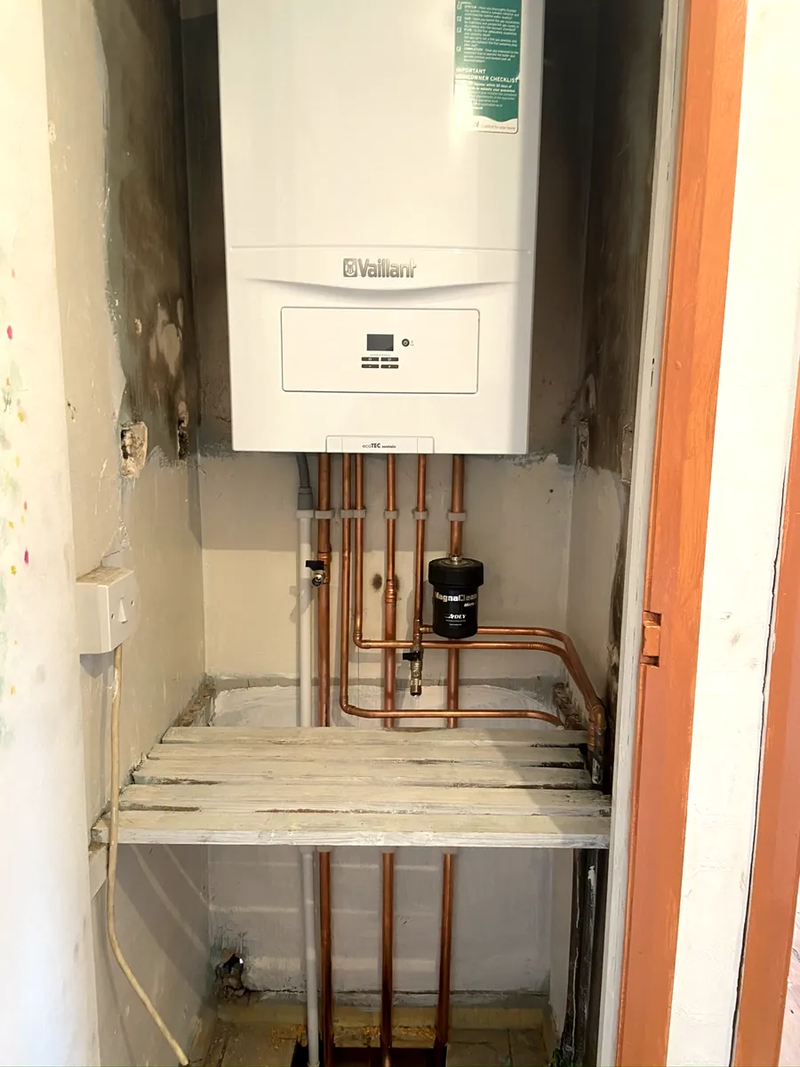 Boiler above an airing cupboard shelf with copper pipe runs